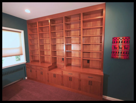 14ft floor-to-ceiling Sapele hardwood library; 10 slab doors, 5 open bookcase bays, and secretary style cabinetry.