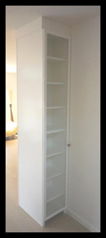 White floor-to-ceiling bookcase back side of entertainment center with 1/4'' glass paneled door.