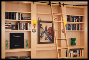 Custom L shaped maple bookcase with rolling ladder and sconce lights.