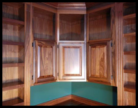 Walnut home library built-in with raised-panel cabinetry doors and integrated upper open-face storage. No particle board.