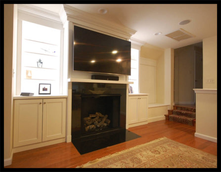 White Mission style entertainment center with LED-lit bookcases, wide crown molding, and a custom lift-up storage compartment.