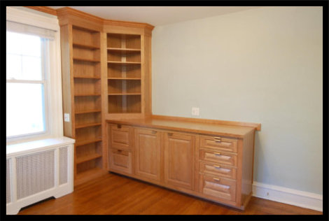 Cherry wood attorney office cabinetry with 45 degree corner bookcase, raised panel doors, and custom file drawers.
